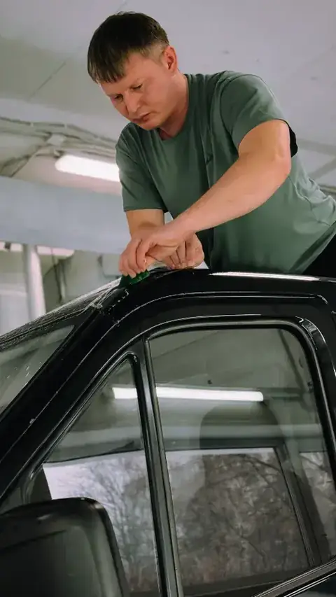 Hombre aplicando polarizado en la ventana de un auto